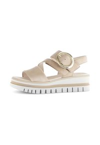 Beige plattform sandaler med två korsade remmar, en rund metallisk detalj och en strukturerad vit sula med ett spårmönster.