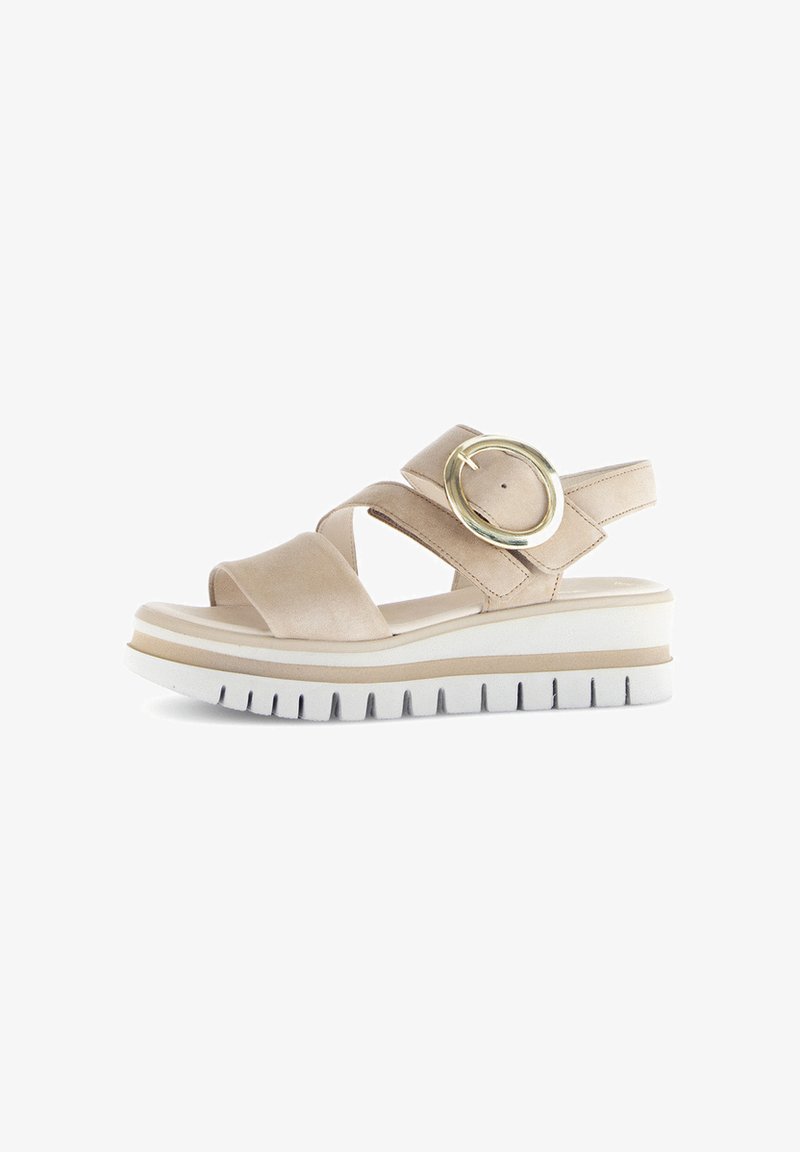 Beige plattform sandaler med två korsade remmar, en rund metallisk detalj och en strukturerad vit sula med ett spårmönster.