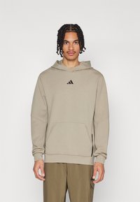 Kapuzensweater van lichtbeige stof met lange mouwen, een voorzak en een zwart logo op de borst. Glad oppervlak en een relaxte pasvorm.