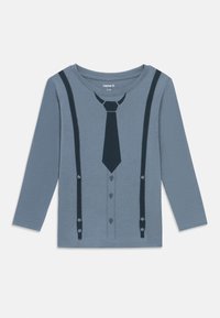 Long-sleeve shirt in light blue with a printed design resembling a suit, featuring a tie and suspenders in dark blue, round neckline, and buttons.