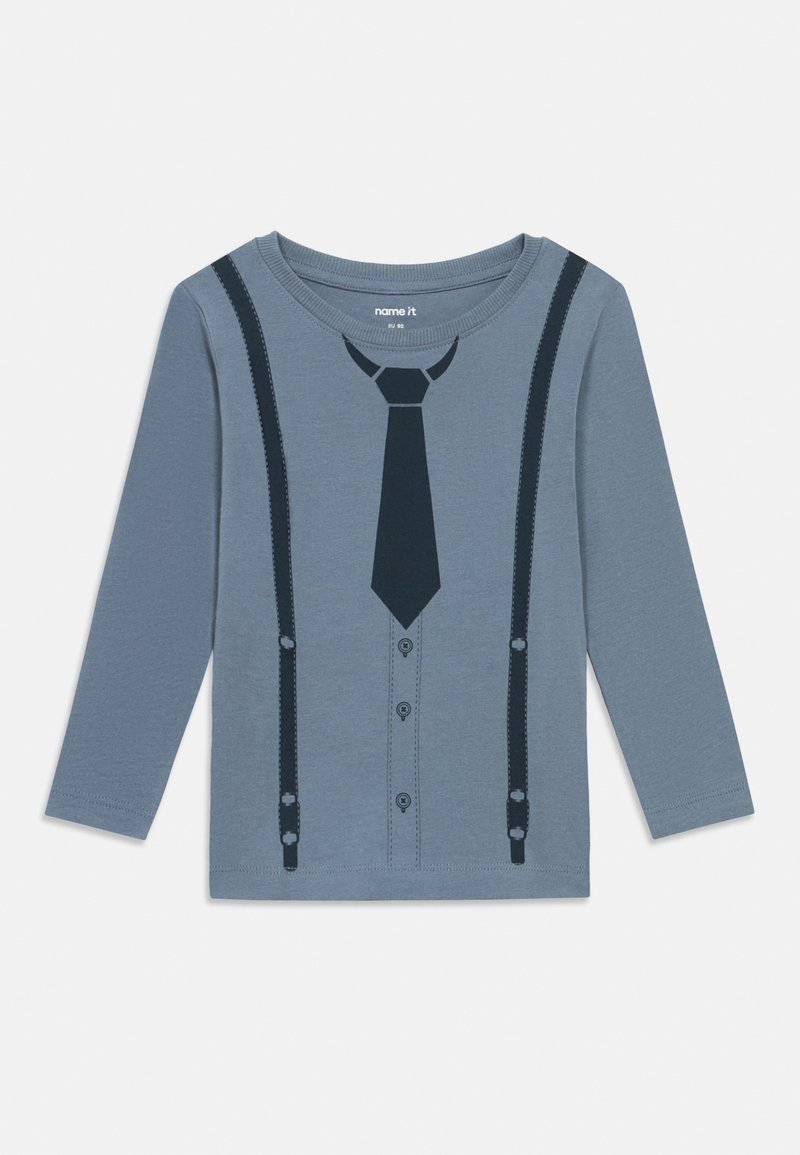 Long-sleeve shirt in light blue with a printed design resembling a suit, featuring a tie and suspenders in dark blue, round neckline, and buttons.