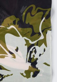 Une écharpe en soie à motifs présente un design abstrait dans des tons de vert olive, noir et blanc. Les bords sont soigneusement finis, ce qui met en valeur sa texture.