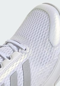White athletic shoe with textured mesh upper, reflective accents, and a grey logo. Features integrated lacing and a smooth toe cap.