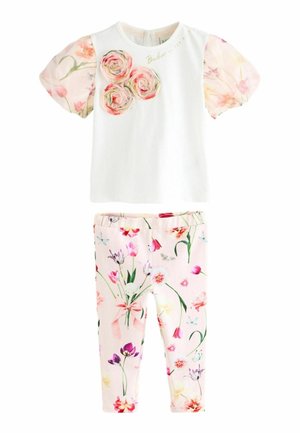 Haut blanc à manches courtes avec appliques de roses roses et manches bouffantes fleuries, associé à un legging imprimé floral rose clair.