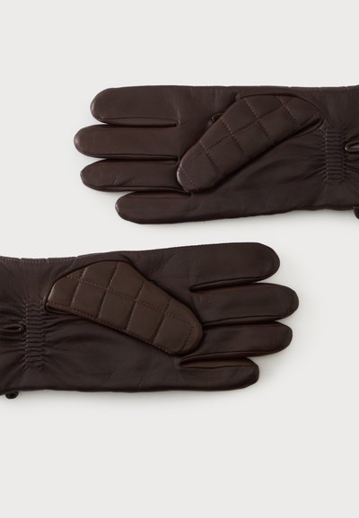 Paire de gants en cuir marron foncé avec des patches matelassés sur les pouces, présentée sur un fond clair uni.