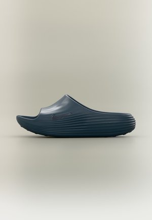 Единичен тъмносин слип-он сандал с текстурирана подметка и лого на Nike swoosh на неутрален фон.