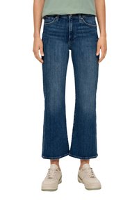 Donkerblauwe denim wide-leg jeans met een middelhoge taille, vijf zakken en een lichte slijtaging aan de zoom. Gepaarde met lichte sneakers.