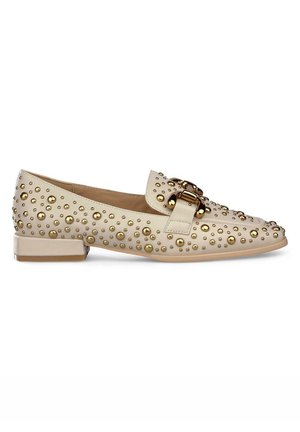 Mocassin beige à bout rond, présentant une surface texturée parsemée d'accents circulaires dorés et une boucle dorée sur l'empeigne. Talon plat.