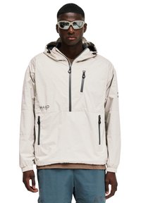 Helle beige Pulloverjacke mit Kapuze, ausgestattet mit einem Reißverschluss-Fach auf der Brust und seitlichen Taschen, elastischen Bündchen und einem subtilen Strukturmuster.
