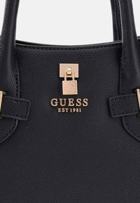 Borsa a mano in pelle nera con finitura testurizzata, caratterizzata da hardware color oro, chiusura a scatto e logo in rilievo "GUESS EST 1981".
