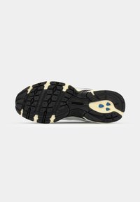La suola della scarpa presenta gomma nera con un motivo testurizzato, accenti beige chiaro e dettagli blu; progettata per trazione e durata.
