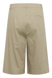 Shorts beiges en tissu texturé. Ils possèdent une poche arrière unique et une coupe droite qui s'étend jusqu'au genou.