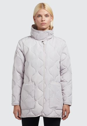 Gequilted lichtgrijze jas met hoge kraag, drukknoopsluiting, twee zijzakken en een gladde, zachte textuur. Heeft een gebogen stikselpatroon.
