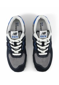 Black and gray sneakers with blue accents, featuring a mesh and suede upper, white laces, and a padded collar. Model 574 by New Balance.