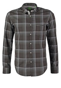 Chemise à manches longues à carreaux gris foncé et noirs, avec poche poitrine et col pointu.