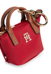 Κόκκινο υφασμάτινο μίνι τσαντάκι με καφέ δερμάτινες λαβές, χρυσά μεταλλικά στοιχεία και ανάγλυφο λογότυπο. Διαθέτει κρίκο για κλειδιά και υφή με ανάγλυφα μοτίβα.