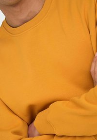 Langarm sweatshirt in helder mosterdgeel, gemaakt van zachte stof met een geribde kraag en manchetten, die een gladde textuur laat zien.