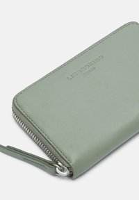 Zielony skórzany portfel o fakturowanej powierzchni, wyposażony w srebrny zamek błyskawiczny z uchwytem. Na przedniej części wytłoczone logo. Prostokątny kształt.