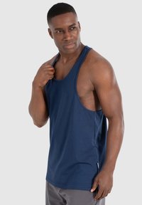 Top in cotone di colore blu navy, caratterizzato da un taglio rilassato, ampie aperture per le braccia e scollatura arrotondata, con dettagli discreti sulle cuciture laterali.