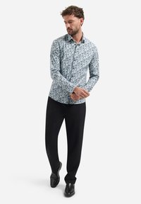 Langarmshirt van een lichtblauwe stof met een vogelpatroon; gecombineerd met zwarte broeken en zwarte schoenen. Slim-fit ontwerp.