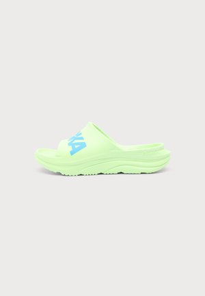 Lysegrøn slip-on sandal med blå tekst på den øverste rem, med tekstureret sål og let hælhøjde.