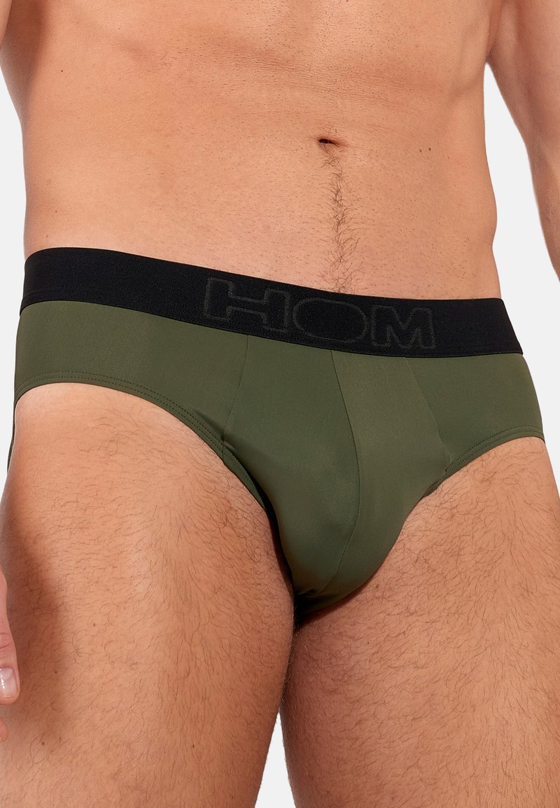 Oliwkowe slipy z miękkiej, elastycznej tkaniny. Posiadają czarny elastyczny pasek z wytłoczonym logo "HOM", co zapewnia dopasowany krój.