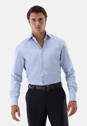 Hellblaues Langarmhemd mit Karomuster, Knopfverschluss vorne und einem schicken Kragen. Getragen mit dunklen Hosen und einem schwarzen Gürtel.