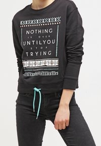 Sudadera negra de manga larga con texto multicolor y detalles estampados. Incluye un cordón turquesa y un corte relajado.