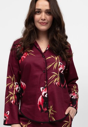 Haut de pyjama en satin bordeaux avec des imprimés de pandas rouges et de bambou, boutons noirs et passepoils noirs au niveau des poignets et du col.