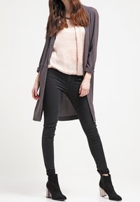 Lång grå cardigan, ljusrosa topp, svarta skinny jeans och svarta ankelstövlar med silverklackar. Slät tyg med avslappnad passform.