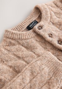 Beige knitted cardigan made from soft, textured material. Features a round neckline, ribbed cuffs, and three brown buttons along the front.
