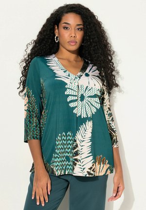 Teal blouse met een V-hals en driekwartmouwen, met een bloemen- en varensprint in wit, oranje en groen. Glad, lichtgewicht materiaal.
