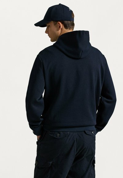 Felpa con cappuccio blu navy con coulisse, realizzata in tessuto morbido, abbinata a pantaloni cargo scuri con tasche con bottoni e finitura strutturata.