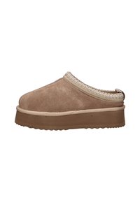 Mocassin en daim brun à enfiler avec une semelle épaisse et une bordure tressée autour de l'ouverture, sur un fond blanc.