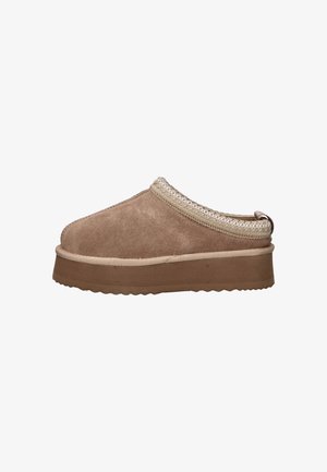 Mocassin en daim brun à enfiler avec une semelle épaisse et une bordure tressée autour de l'ouverture, sur un fond blanc.