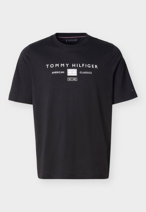 T-shirt noir à manches courtes et col rond avec texte blanc « Tommy Hilfiger American Classics Est. 1985 » et logo centrés sur la poitrine.