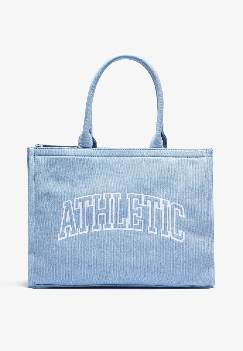 Lyseblå canvas tote bag med to hanke, der har hvidt buet tekst "ATHLETIC" på fronten. Simpelt rektangulært design.