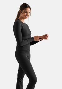 Black long-sleeve top and leggings made of stretchy fabric, featuring a fitted design and minimal seams for comfort and mobility.