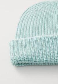 Šviesiai mėlynas megztas skrybėlė su briaunotu paviršiumi ir pasukta kraštu. Minkšta medžiaga su jaukia išvaizda.