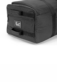 Black fabric duffel bag with a rectangular shape, zipper closure, two side handles, and a clear label pocket on the front.