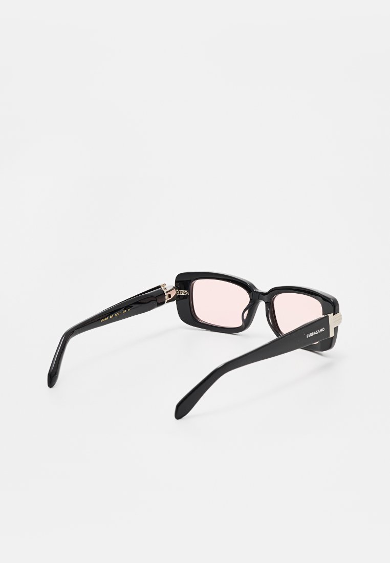 Gafas de sol rectangulares negras de Ferragamo con lentes de color rosa y detalles plateados en las patillas, mostradas desde un ángulo trasero.