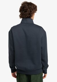 Navy sweatshirt with a high collar, ribbed cuffs and hem, made from soft fabric, featuring a relaxed fit and minimal design details.