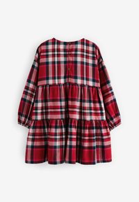 Robe à carreaux rouges avec des manches longues, design à volants et fermeture à boutons au dos. Présente des accents de motifs horizontaux et verticaux.