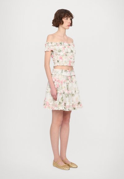 Off-the-shoulder floral crop top and layered skirt, both with pink and green flower patterns. Woven gold flats complete the outfit.
