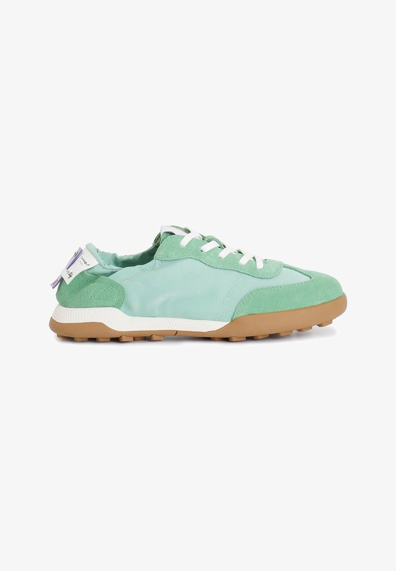Light green sneakers with a mix of smooth fabric and suede, white laces, textured rubber sole, and a purple tag on the heel.