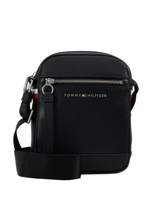 Black Tommy Hilfiger crossbody bag with silver zipper, front logo, adjustable strap, and red-white-blue striped detail on the sides.