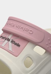 Λευκό και ροζ λουράκι σανδαλιού με το λογότυπο Calvin Klein ανάγλυφο και τυπωμένο στο πίσω μέρος και στην πλευρά.