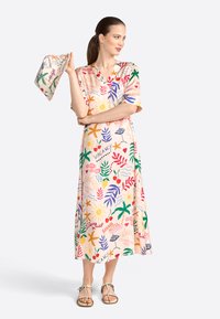 Flowy, knee-length dress in pastel fabric featuring a tropical print with sun, leaves, and colorful text. Includes a matching scarf.