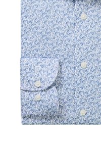 Chemise à manches longues boutonnée avec motif floral bleu et blanc et quatre boutons blancs visibles sur le poignet et à l'avant.