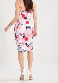 Vestido midi floral con una silueta ajustada y patrones de flores rosas y verdes sobre un fondo claro. Diseño con tirantes y corte a la altura de la rodilla.